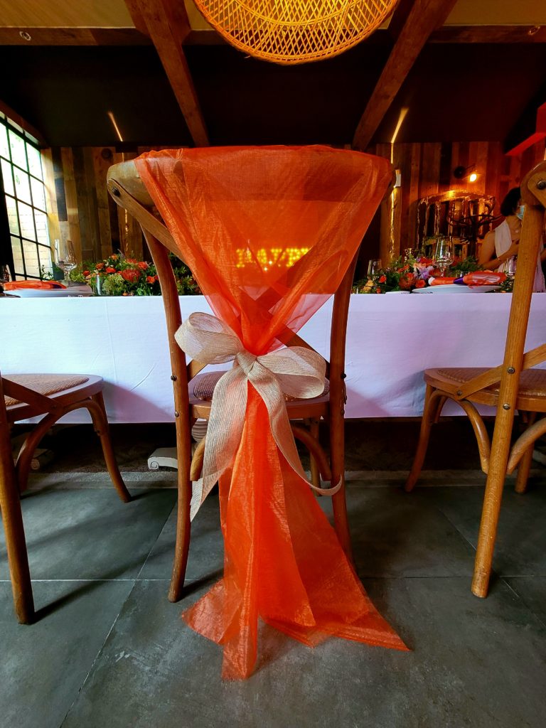 Decorate your chairs to elevate your tablescape. This chairs has a bow tied around it.