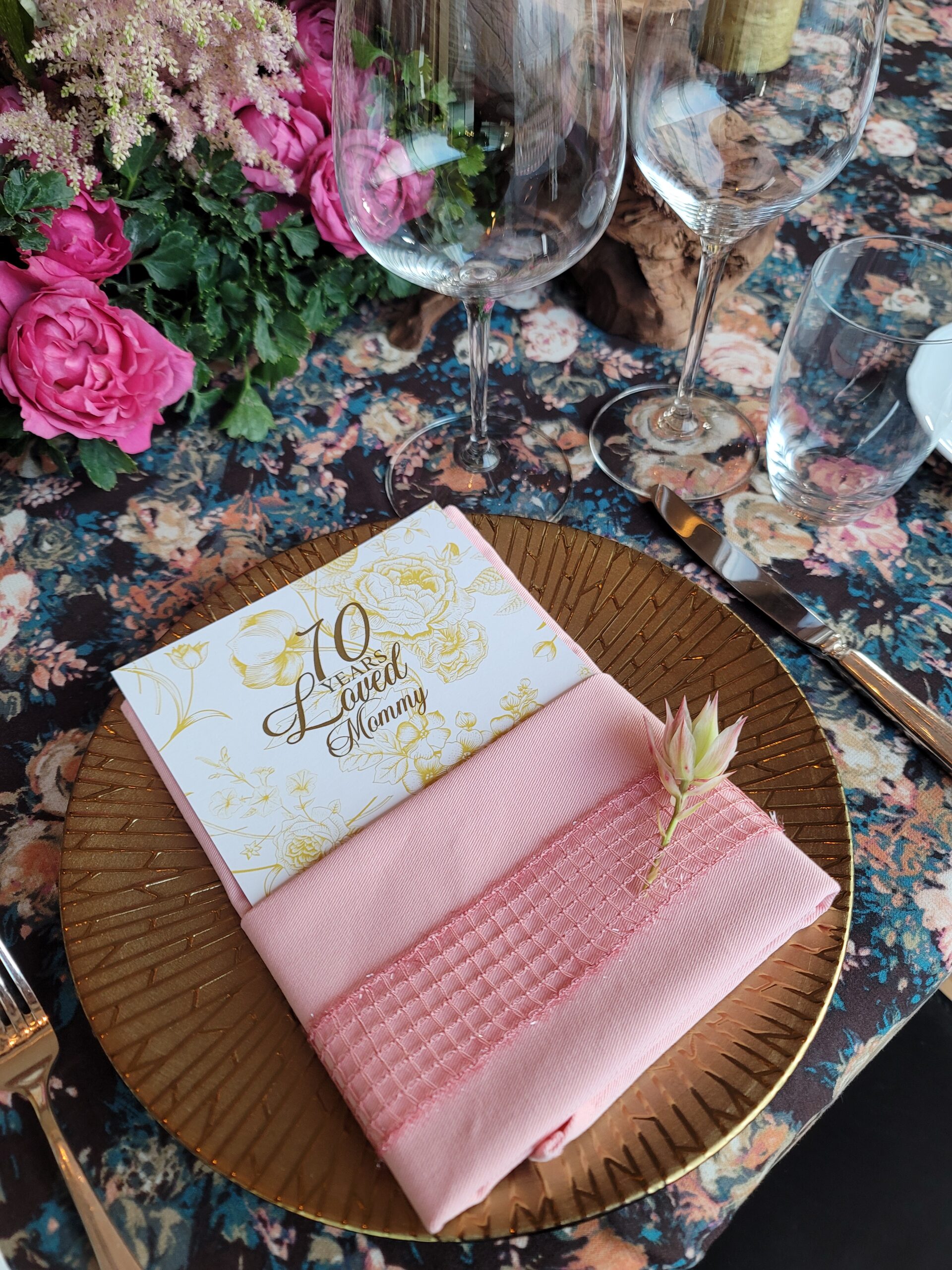 Elegant napkin fold adorned with a textured ribbon and delicate flowers, adding a personalized touch to a sophisticated table setting.