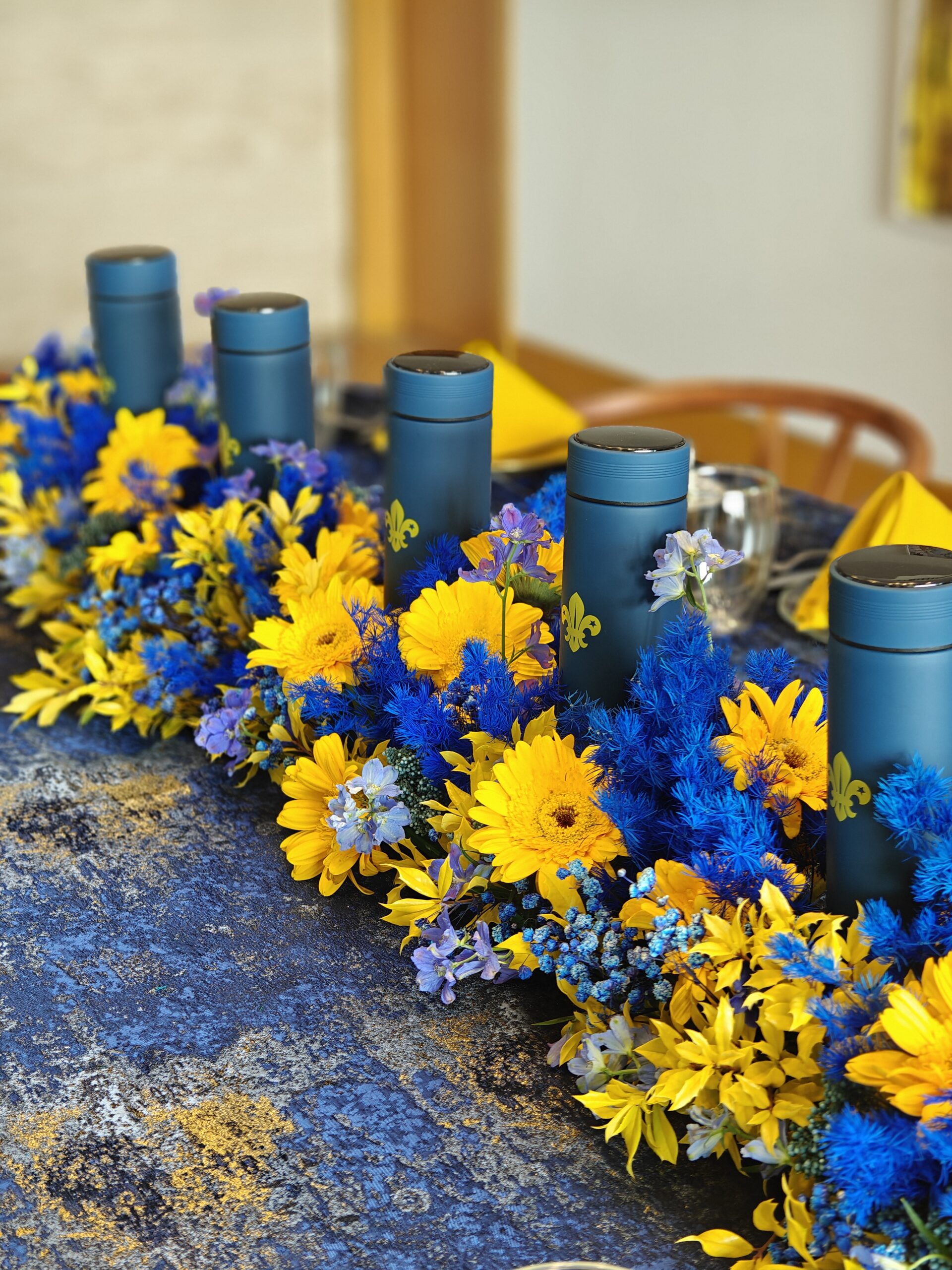 A scouting-themed celebration setup with tents, folding chairs, and thermal flask water bottles as centerpieces, embodying the adventure and tradition.